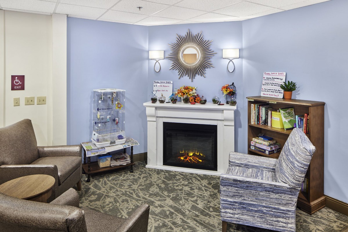 A cozy living room with a fireplace, armchairs, and decorative elements.