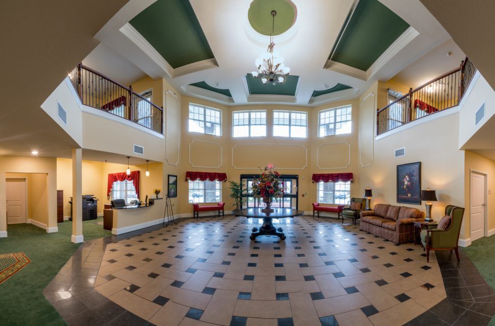 A spacious lobby with a chandelier, large windows, and comfortable seating.