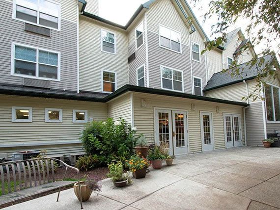 A multi-story residential building with a patio area and potted plants.