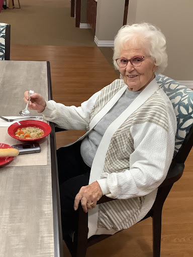 An elderly woman enjoying a meal at the table.