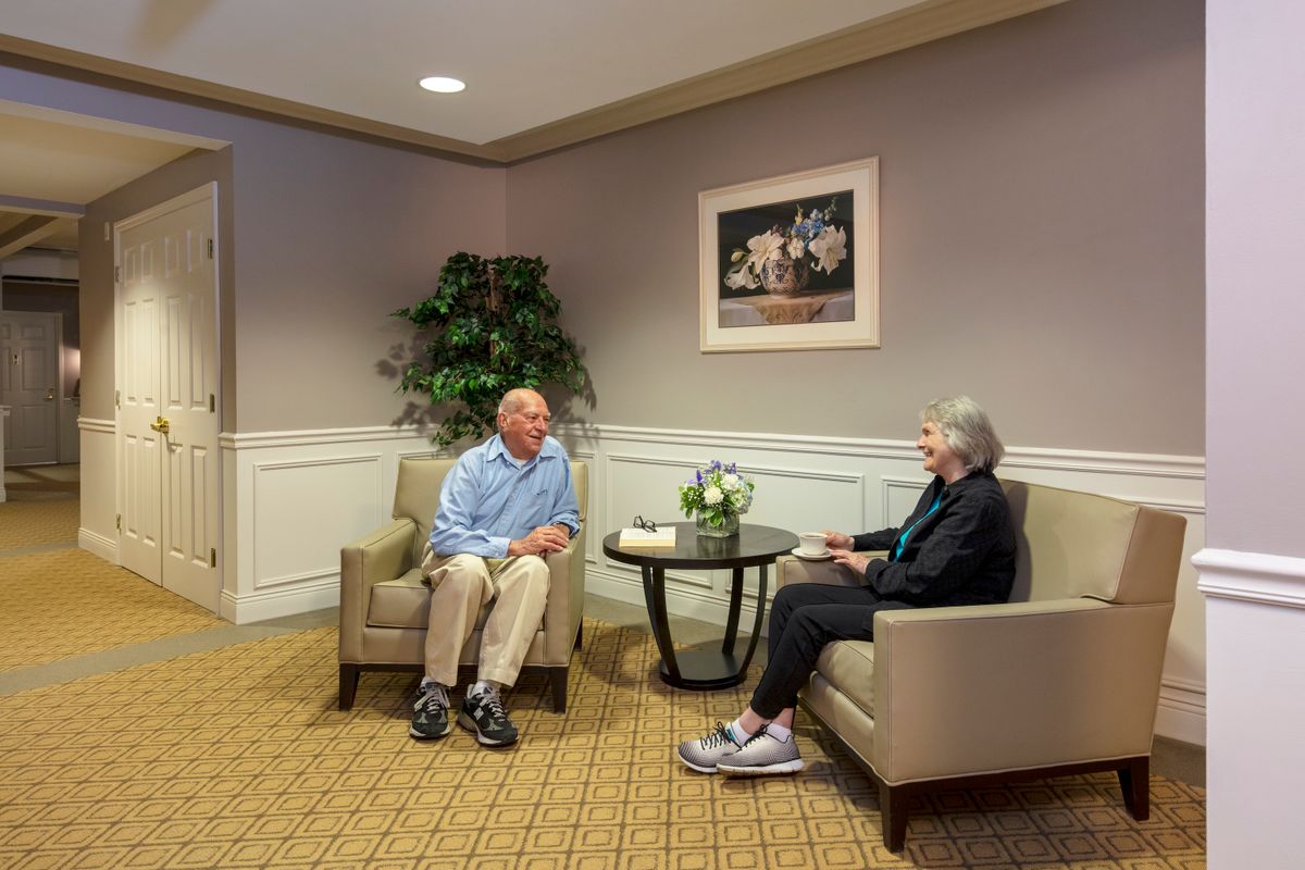 Two elderly individuals engaged in conversation in a cozy living room setting.