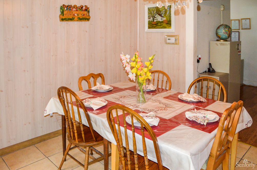 A cozy dining room with a table set for four, featuring a vase of flowers and an inviting atmosphere.
