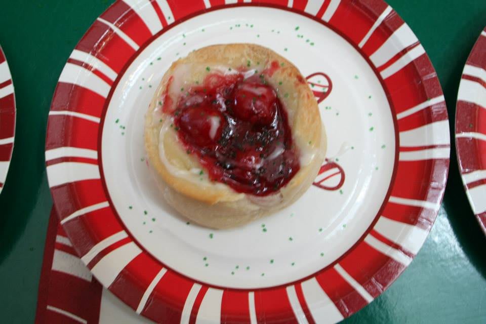 A pastry with cherry topping served on a decorative plate.
