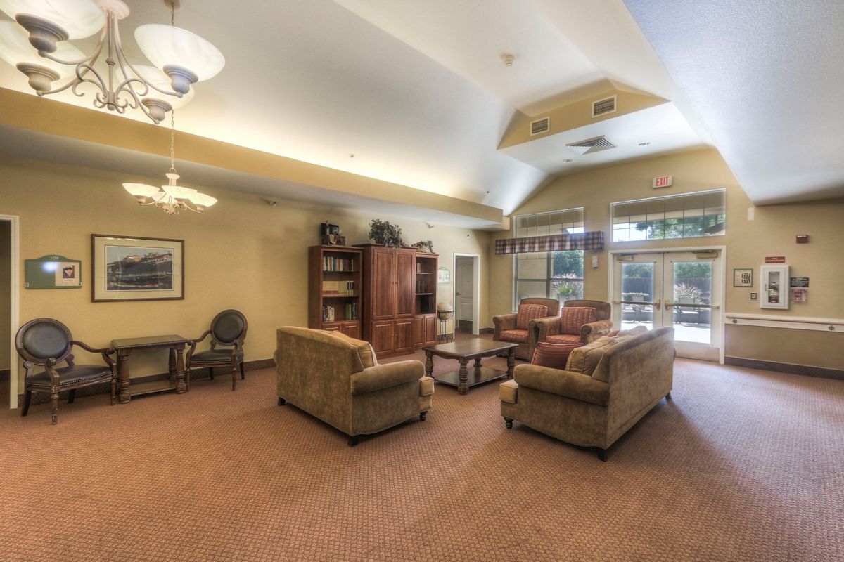 A spacious and well-lit living room with comfortable seating and a bookshelf.