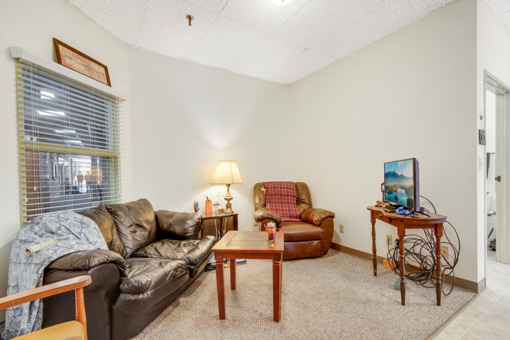A cozy living room with a sofa, armchair, coffee table, and television.