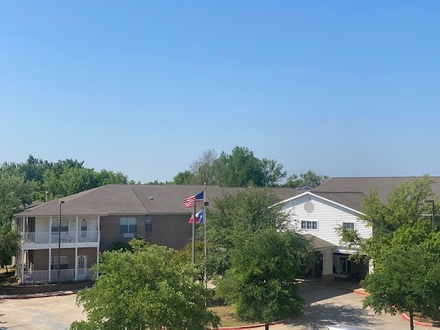A residential building with flags and trees under a clear blue sky.