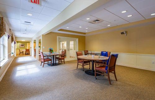 A cozy dining area with several tables and chairs arranged on a carpeted floor.