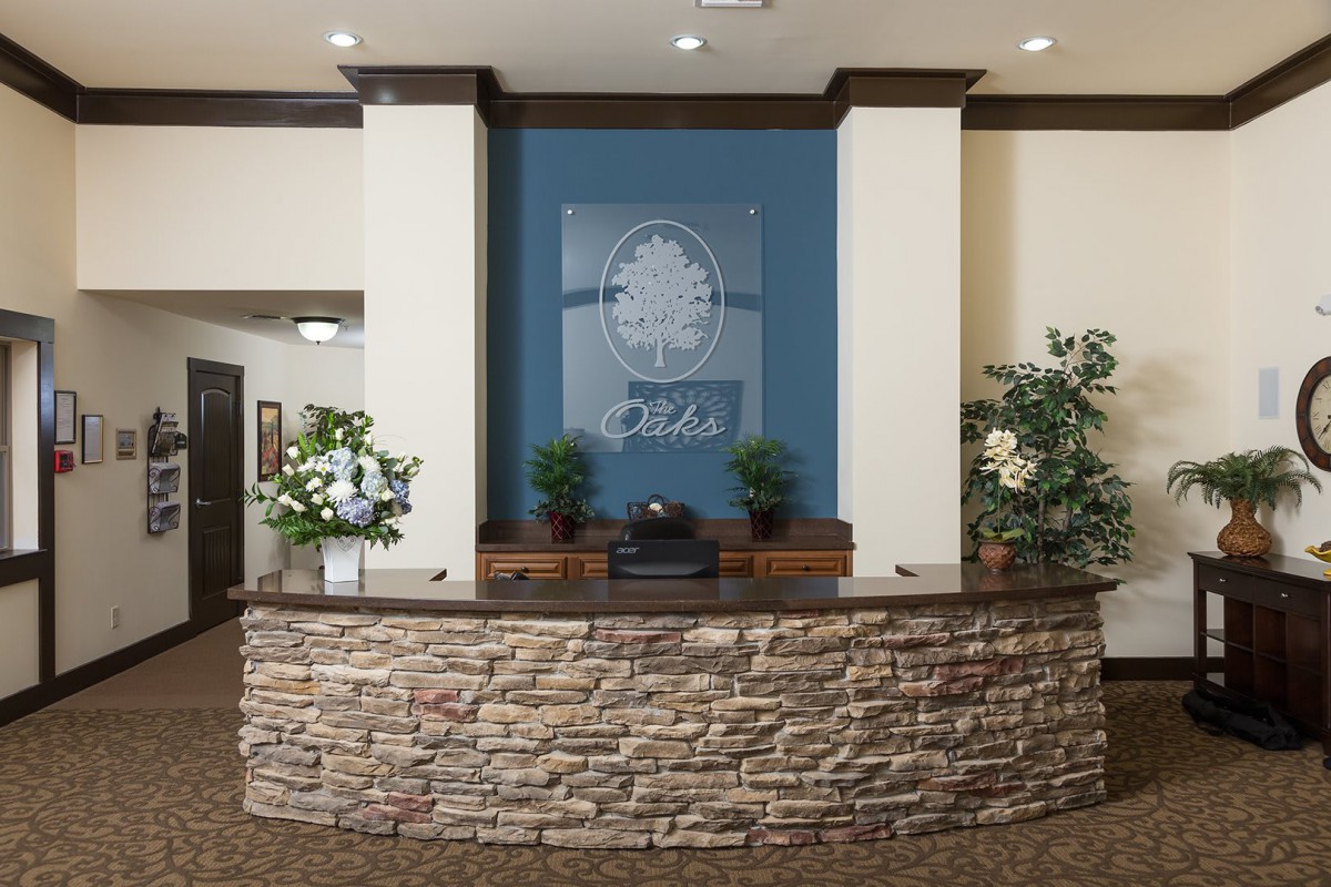 A hotel lobby with a stone reception desk and decorative plants.