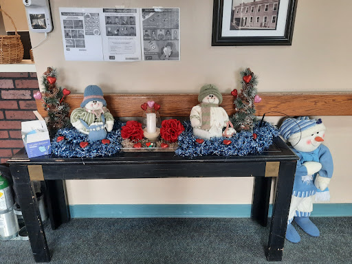 A festive winter-themed table arrangement featuring decorative snowmen, candles, and flowers.