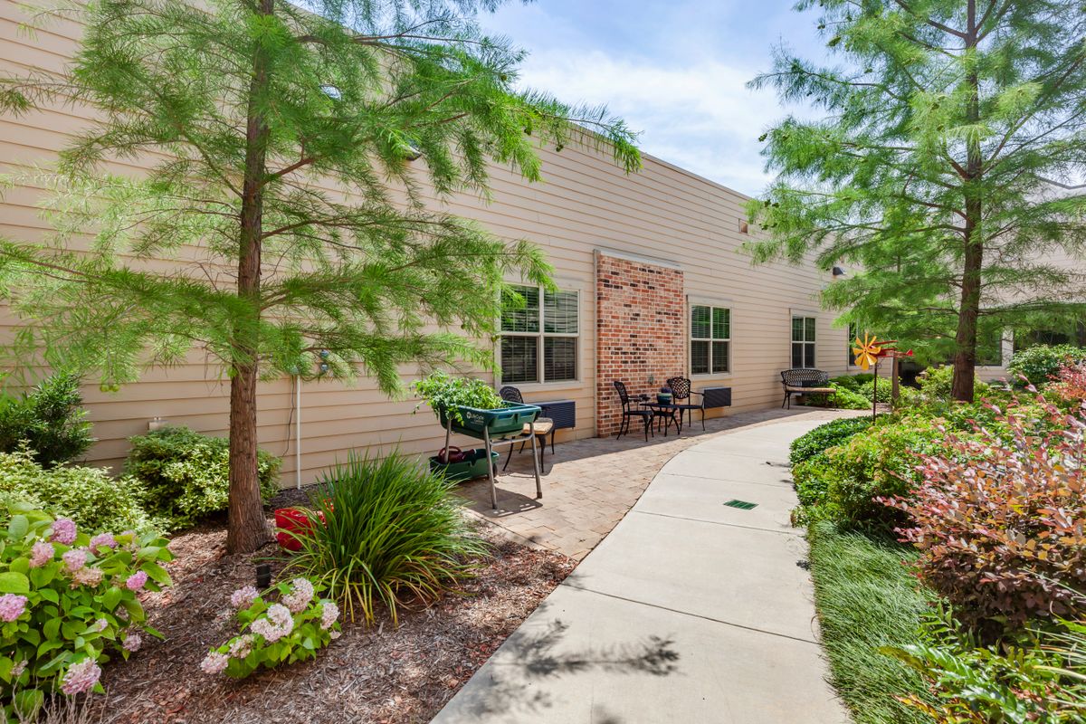 A landscaped pathway with benches and greenery alongside a building.