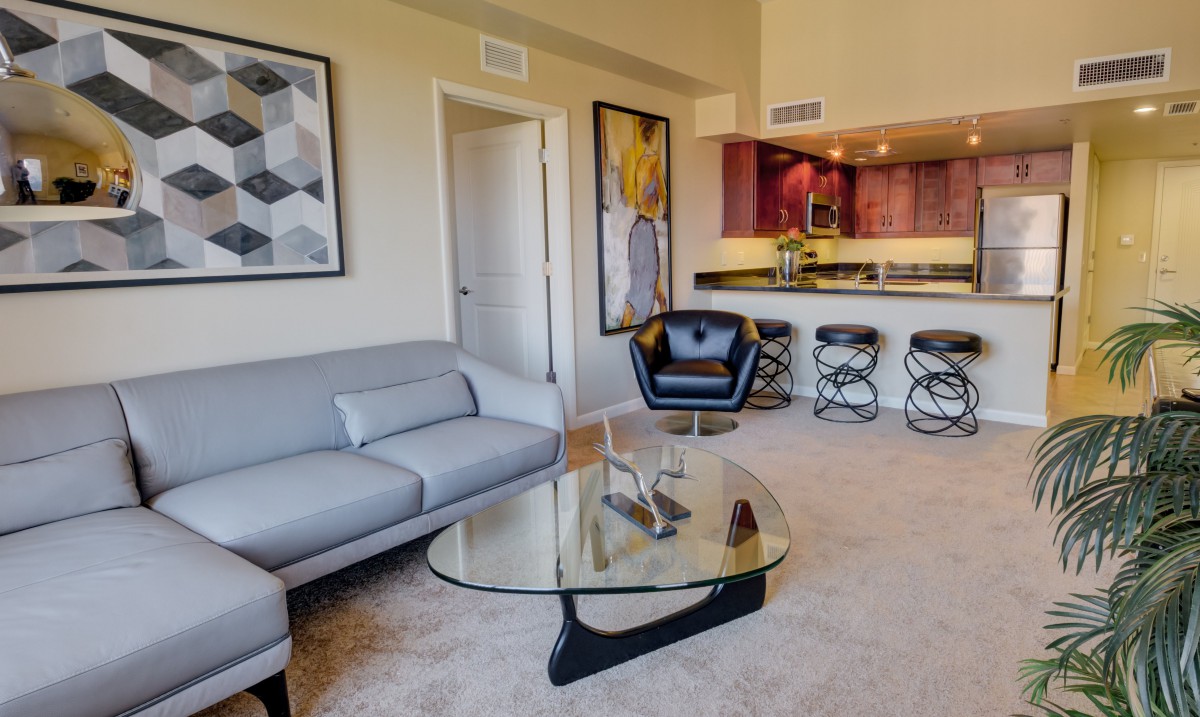 A modern living room with stylish furniture and contemporary artwork, featuring an open plan kitchen area.