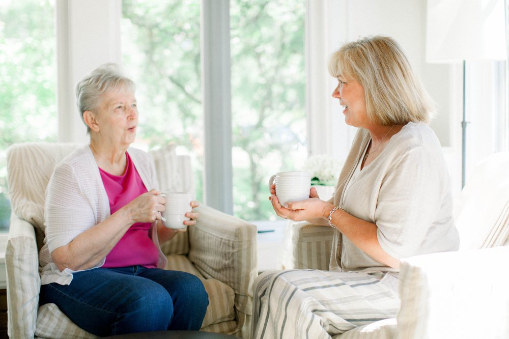 Two women enjoying a casual conversation over coffee in a cozy living room.