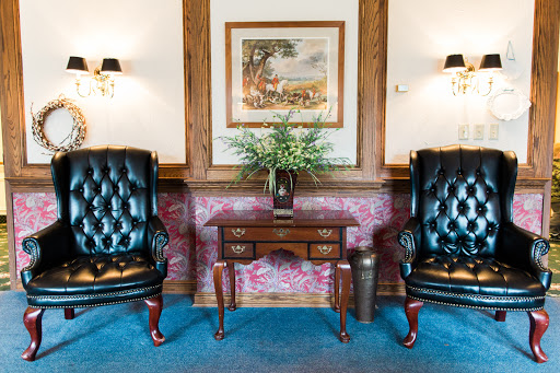 A cozy and elegant living area featuring plush armchairs, a decorative table, and a piece of artwork on the wall.
