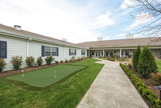 A view of a single-story building with a well-maintained lawn and a concrete pathway leading to the entrance.