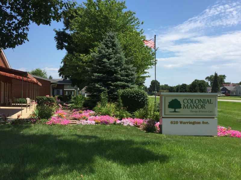 A beautifully landscaped garden with blooming flowers and lush greenery, featuring a sign for Old Town Bluffton.