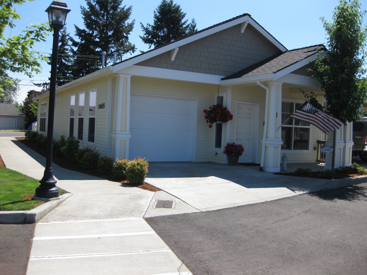 A suburban residential house with a garage and driveway, surrounded by trees.