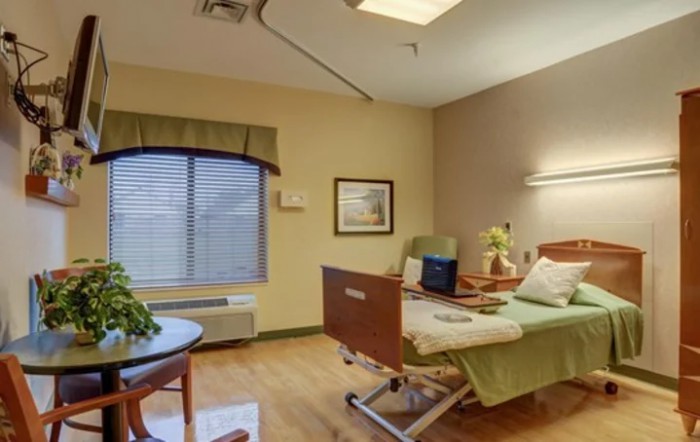 A comfortable hospital room with a bed and seating area.