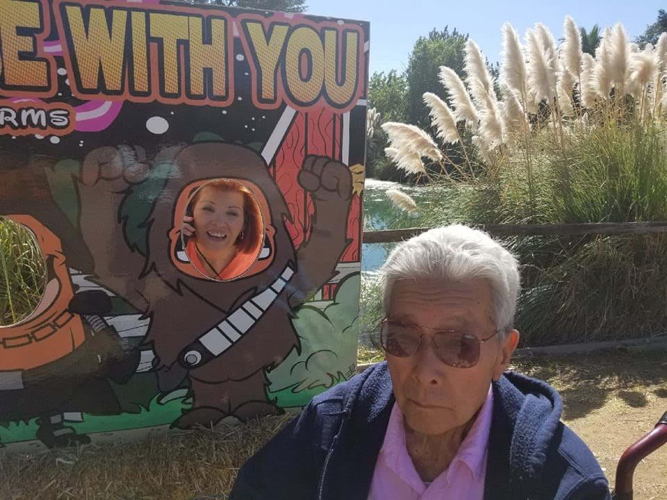 A person posing with a cardboard cutout and another standing nearby outdoors.