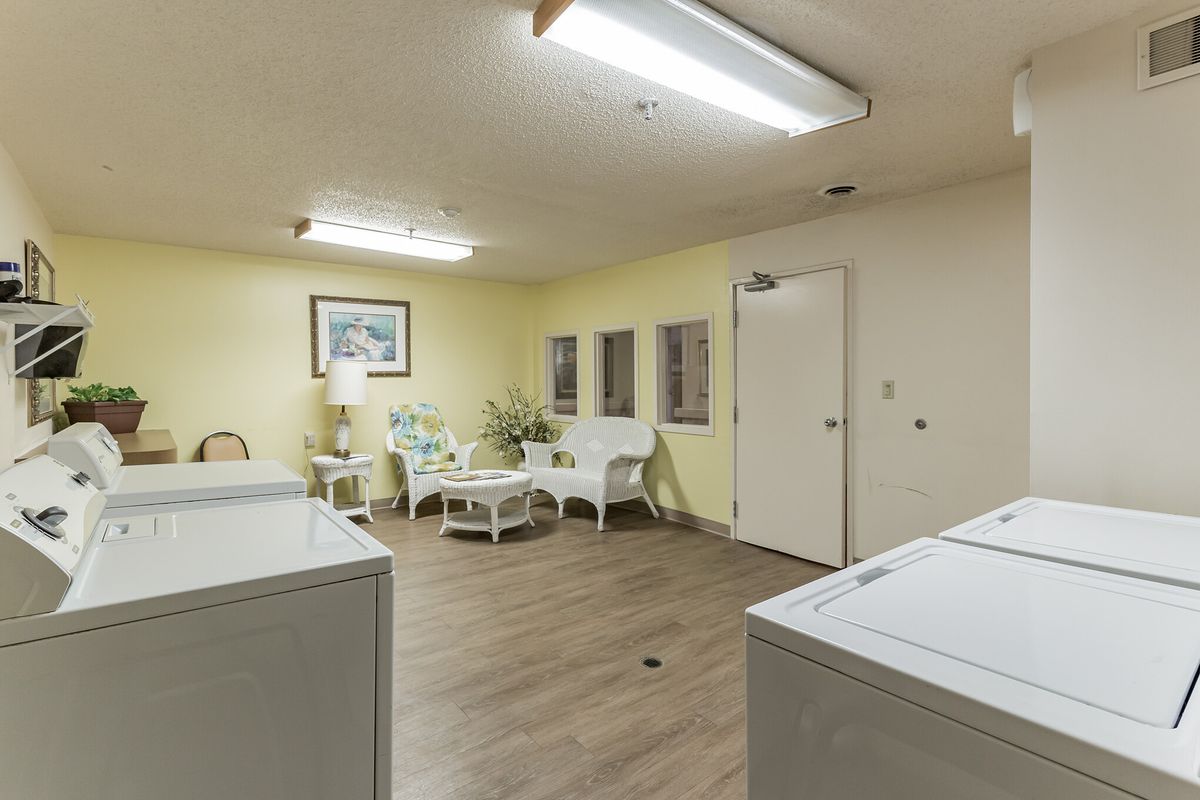 A cozy laundry room with washing machines and a sitting area with chairs and a table.