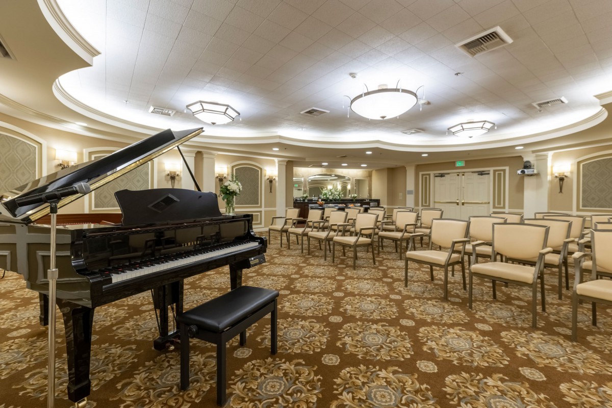 A luxurious concert hall with a grand piano and arranged seating.