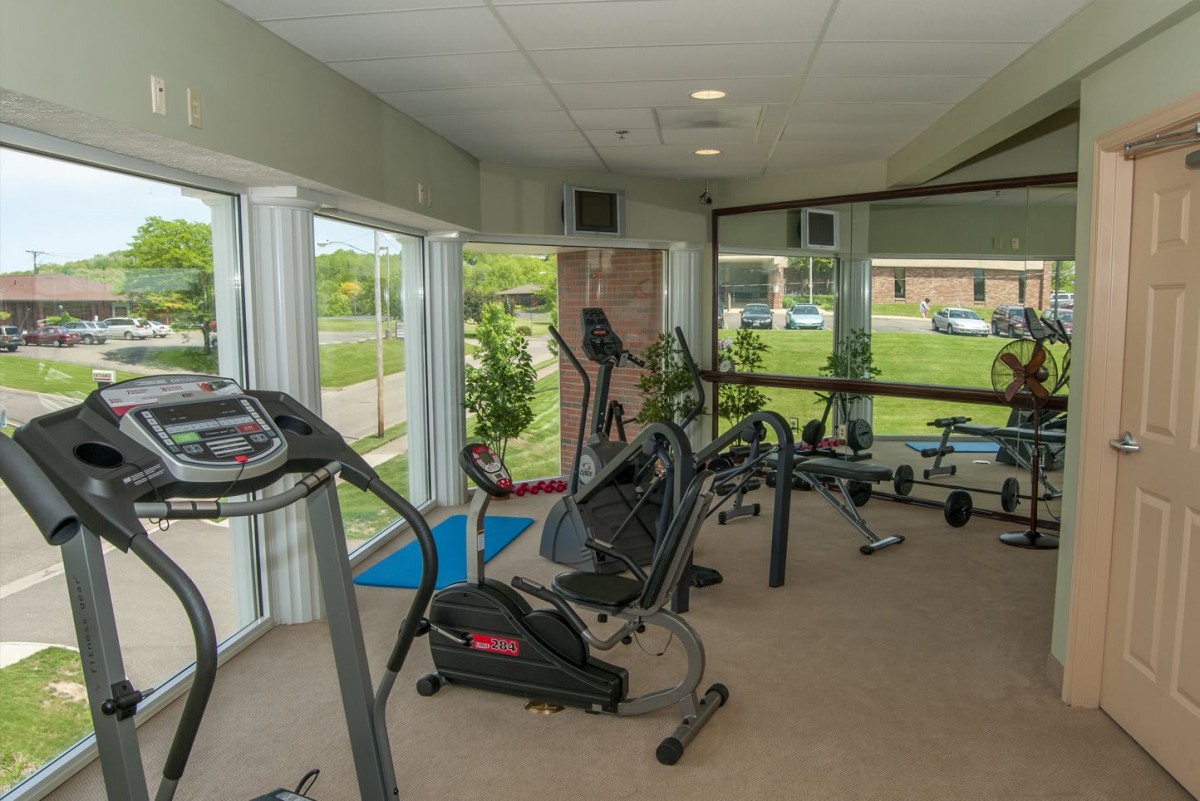 A small indoor gym equipped with exercise machines such as treadmills, ellipticals, and stationary bikes.