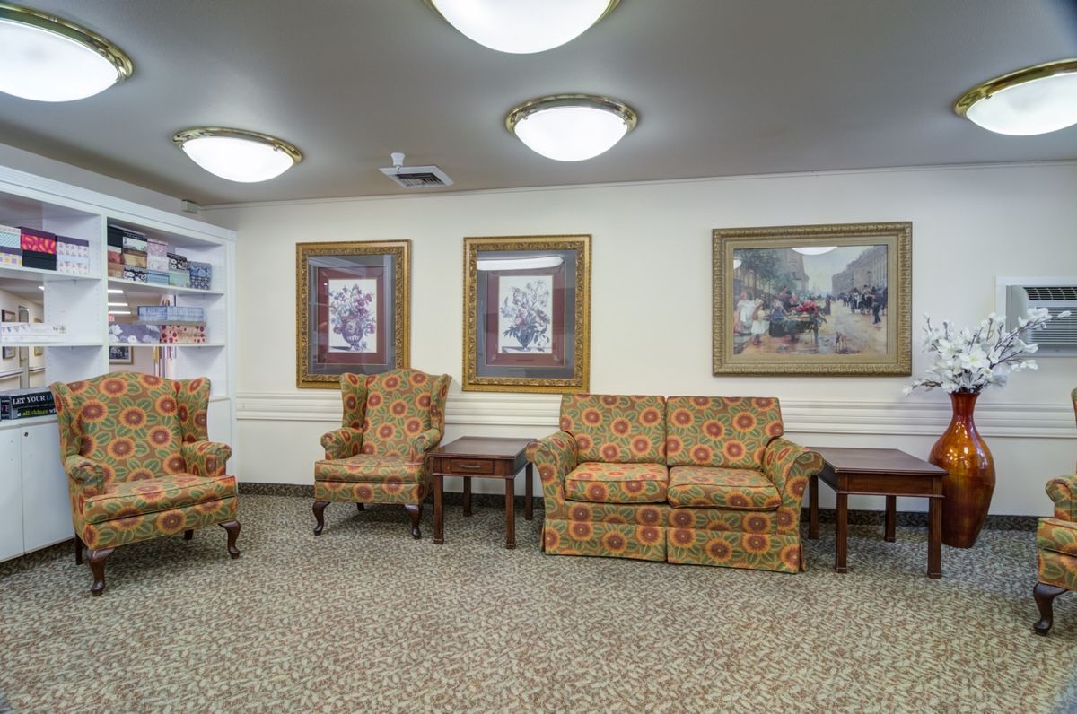 A cozy waiting area with patterned chairs, a sofa, and framed artwork on the walls.