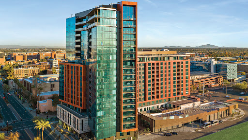 A modern residential skyscraper featuring a vibrant glass facade in an urban setting.