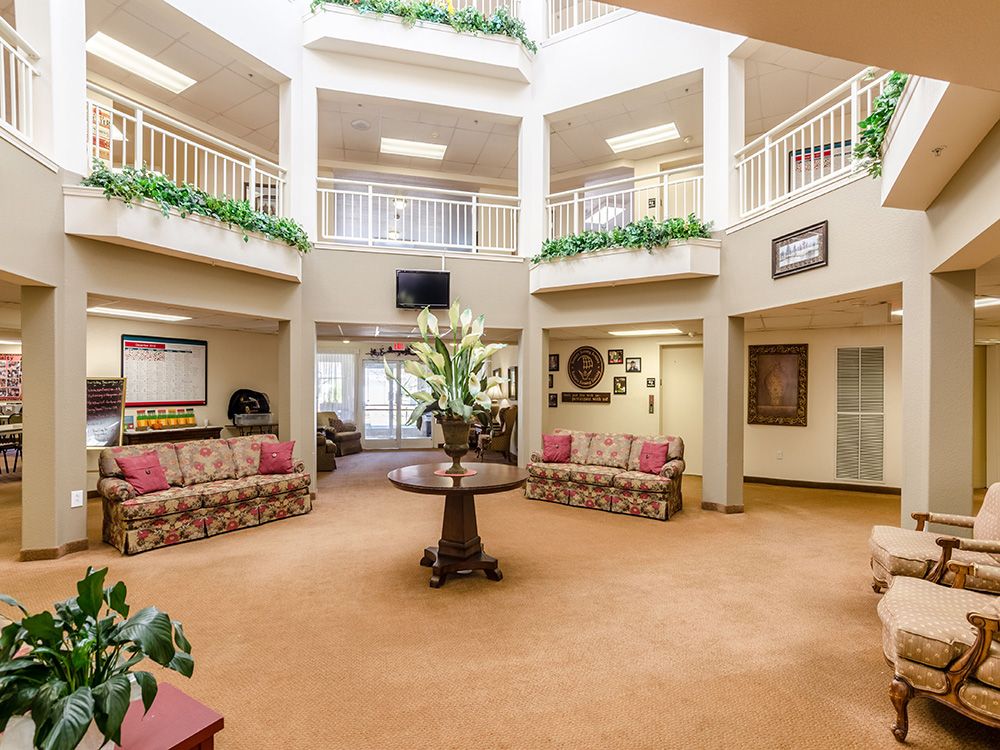 A spacious lobby with elegant furniture, featuring sofas and a central table adorned with decorative plants.