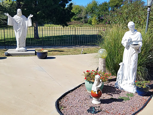 A serene garden featuring two white statues surrounded by decorative plants and stones.