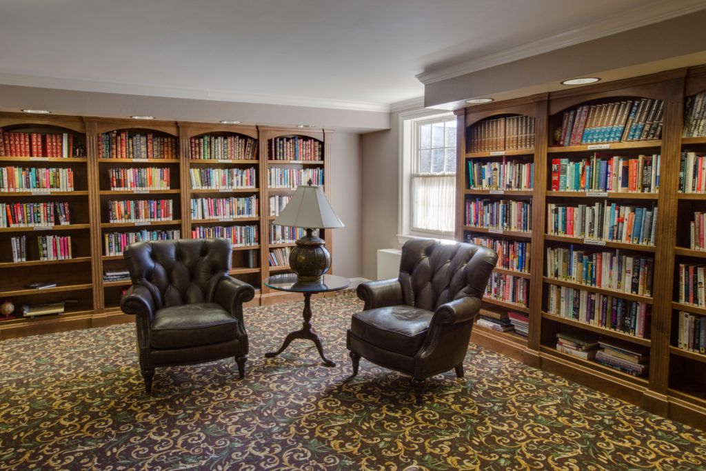 A cozy library corner with two chairs and fully stocked bookshelves.