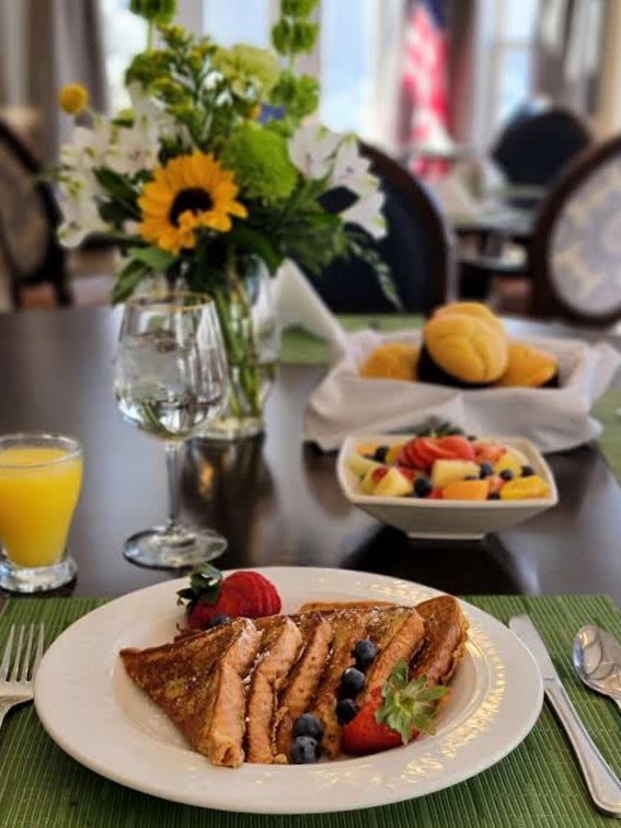 A breakfast table with toast, fruit salad, muffins, and orange juice.
