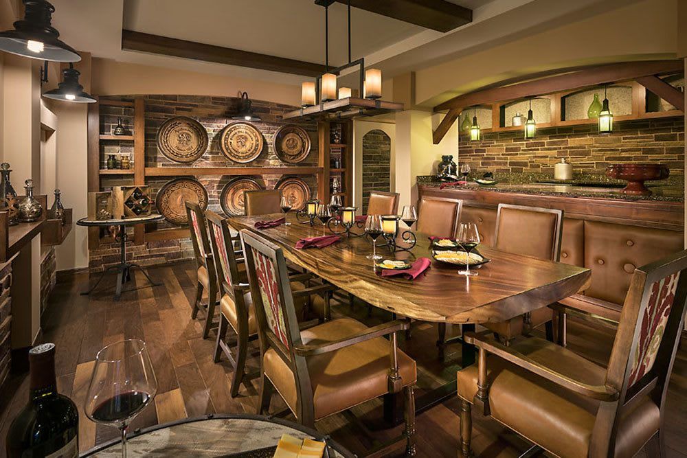 A cozy dining room with rustic decor and wooden furniture, featuring wine barrels and ambient candle lighting.