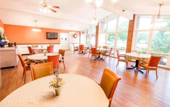 A bright and modern dining area with tables and chairs arranged near large windows.
