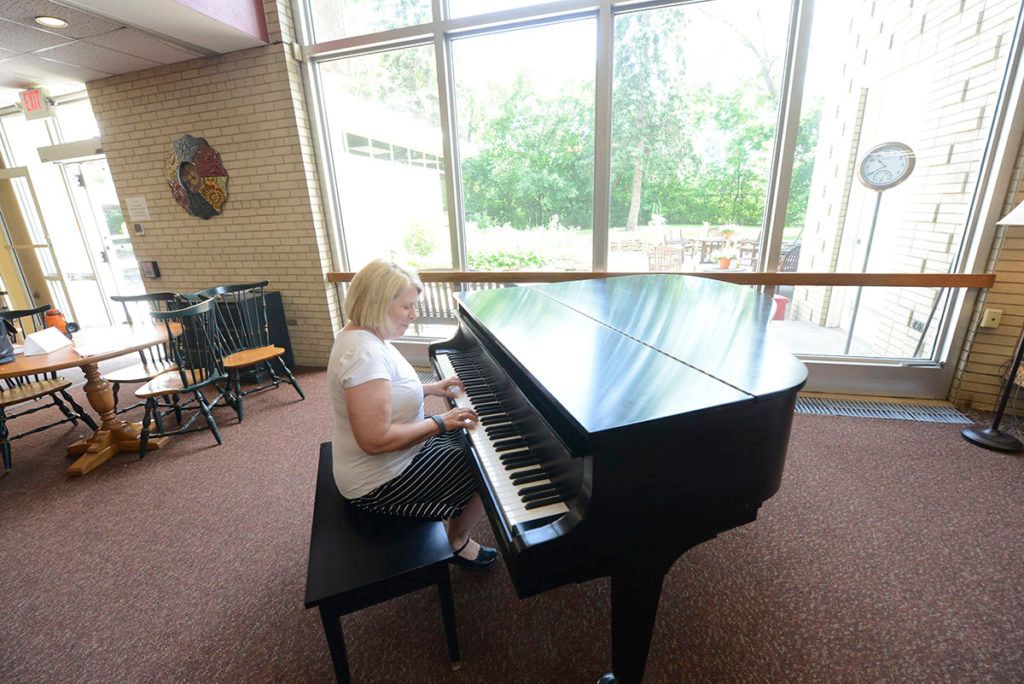 A woman playing the piano in a well-lit room.