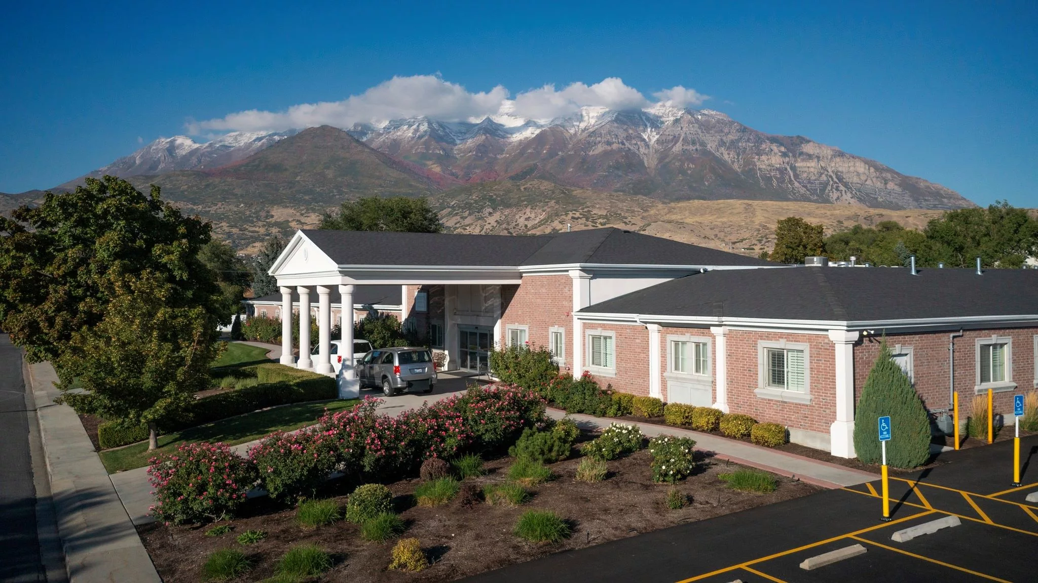 A scenic view of a building with mountains and clouds in the background.