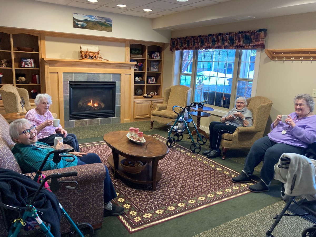 A cozy living room with seniors relaxing near a fireplace.