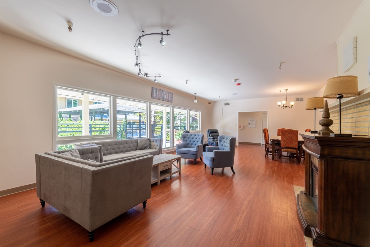 Spacious living room with modern furniture and large windows, featuring a wooden floor.