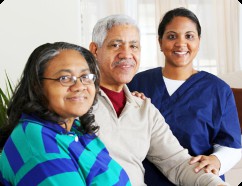 An elderly couple sits with a healthcare professional, showcasing support and care.