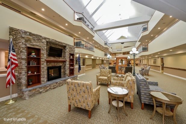 A spacious lobby area with comfortable seating, a fireplace, and a large skylight overhead.