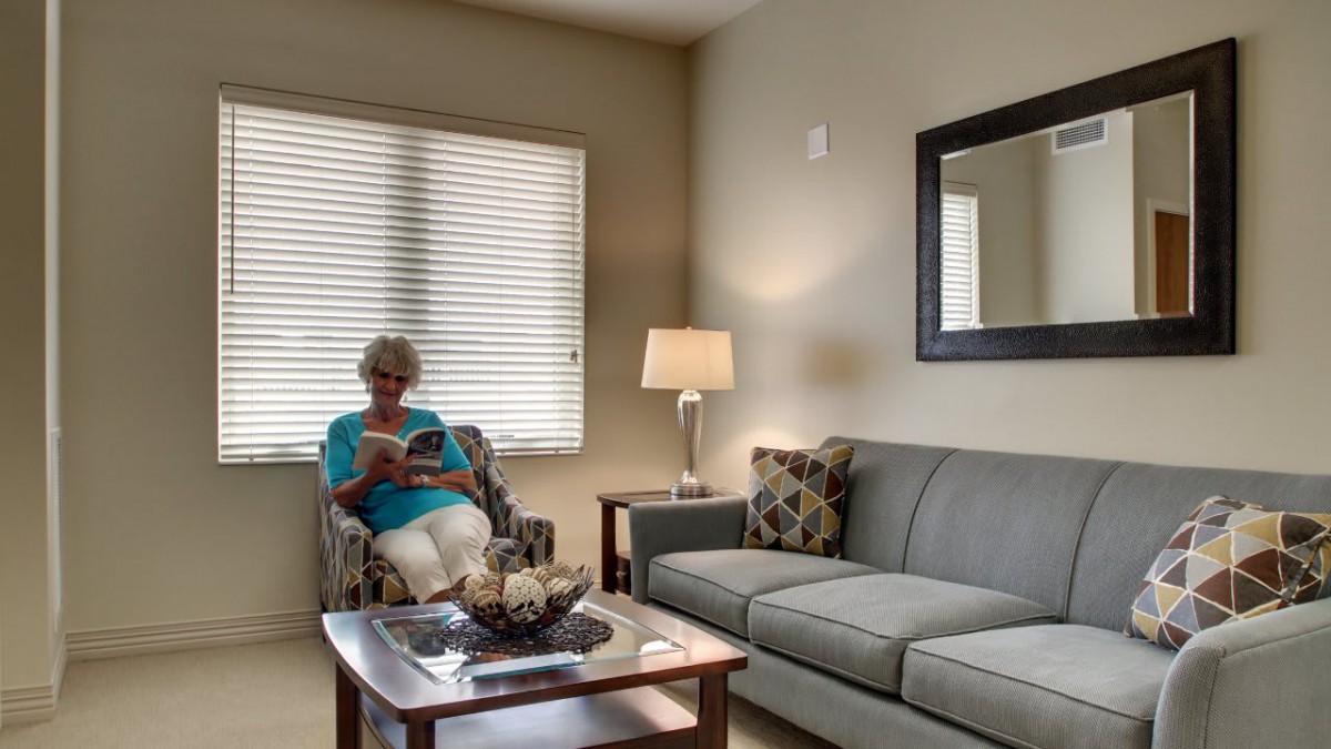 A woman sitting in a cozy living room reading a book.