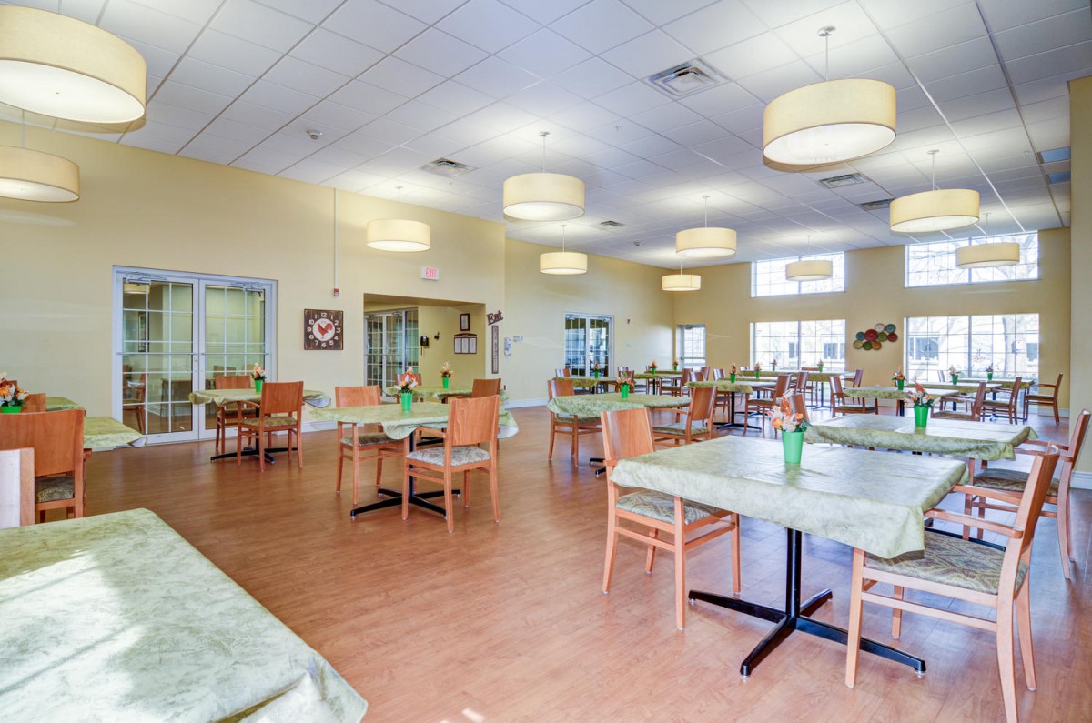 A spacious dining area with neatly arranged tables and chairs, well-lit with modern lighting fixtures.