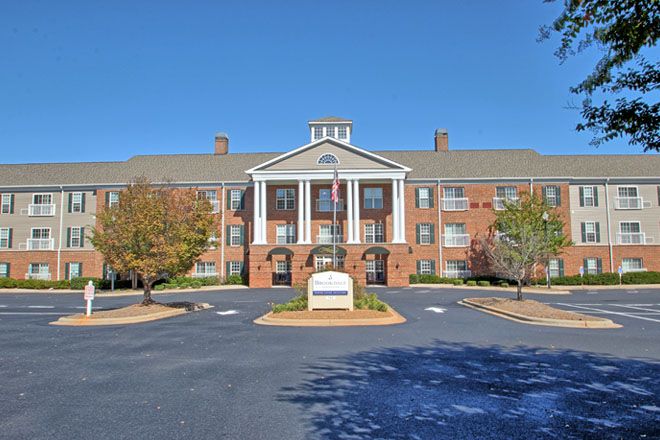 A stately brick building with white columns and a clear blue sky overhead.