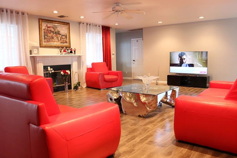 A modern living room with vibrant red chairs and a sleek glass coffee table.