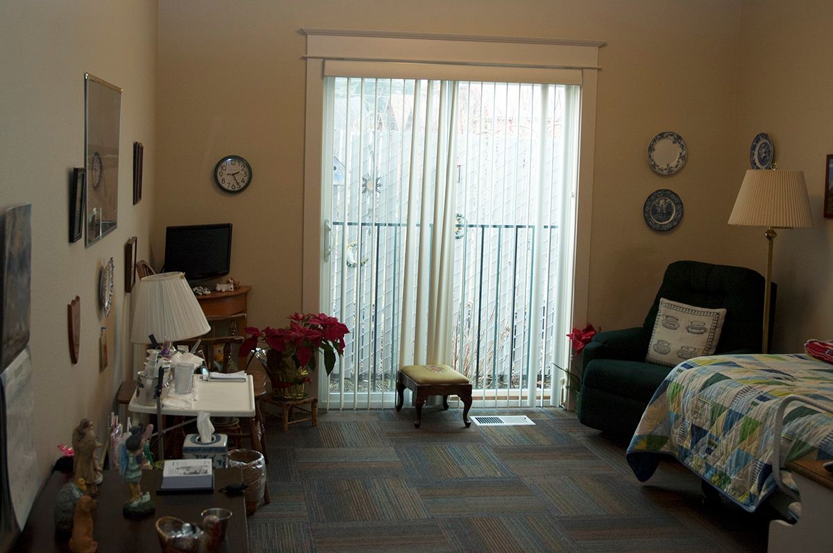 A cozy living room setup with a large window covered by sheer curtains, surrounded by comfortable furniture and decor.
