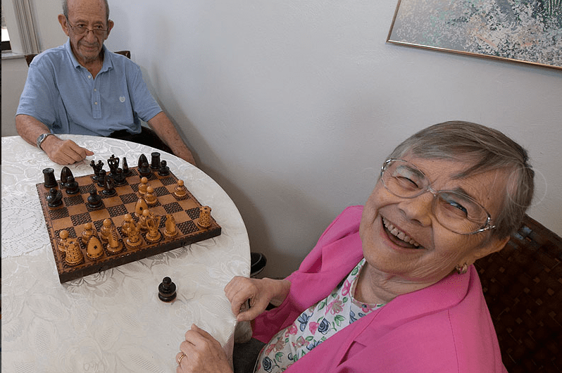 Elderly couple enjoying a game of chess with smiles.