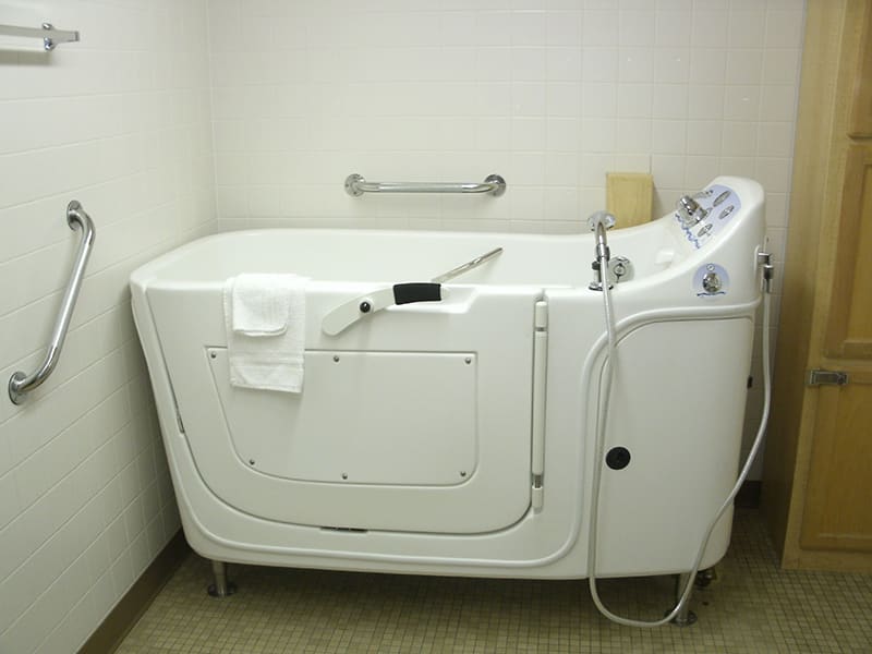 A walk-in bathtub designed for accessible and safe bathing, featuring a side door and handrails.