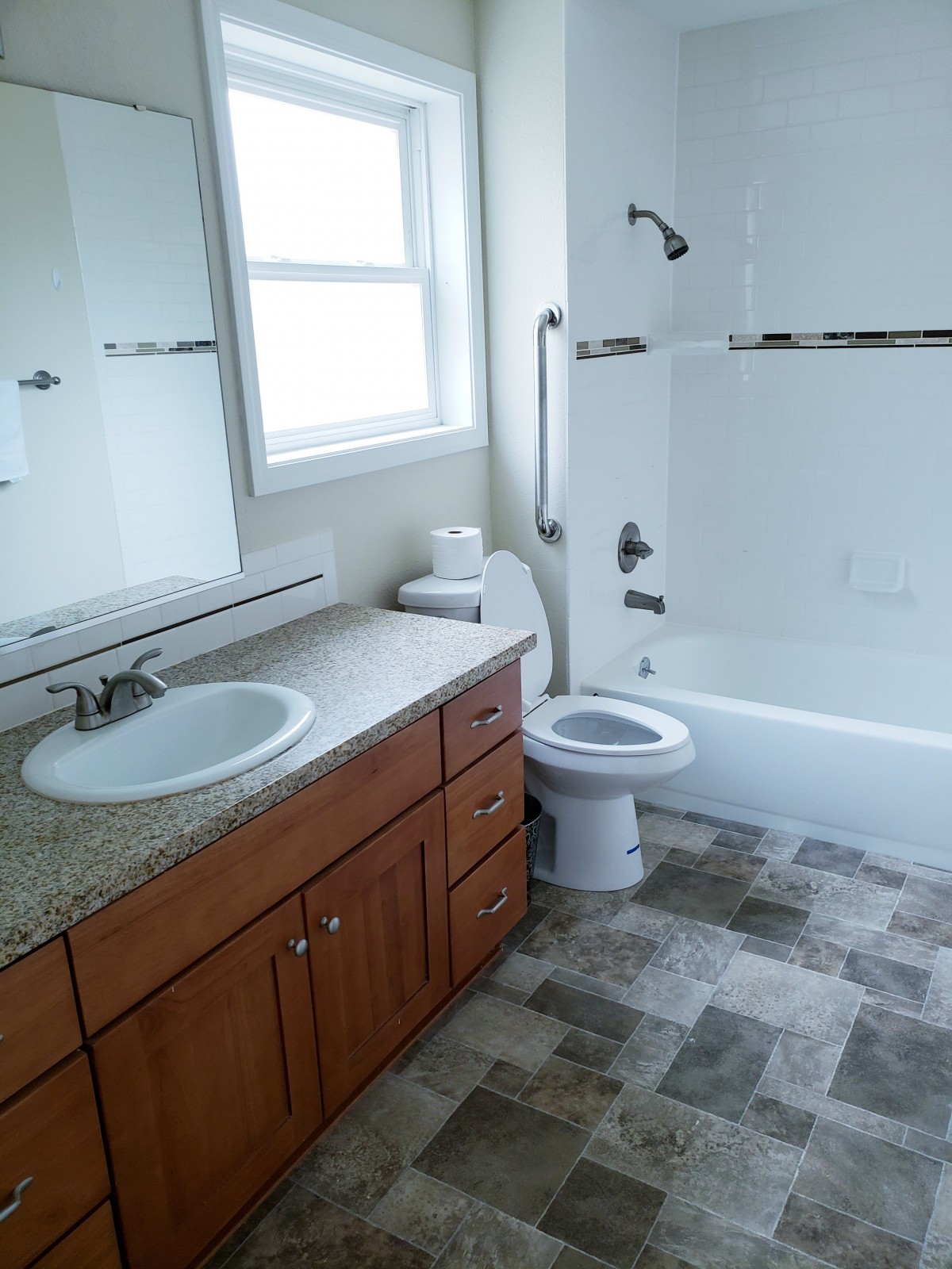 A clean and modern bathroom with a vanity, sink, toilet, and bathtub.