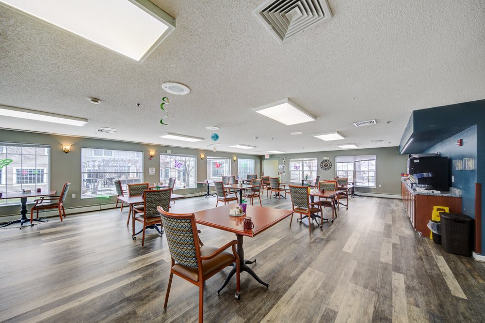 A spacious and modern indoor dining area with several tables and chairs, featuring large windows and stylish flooring.