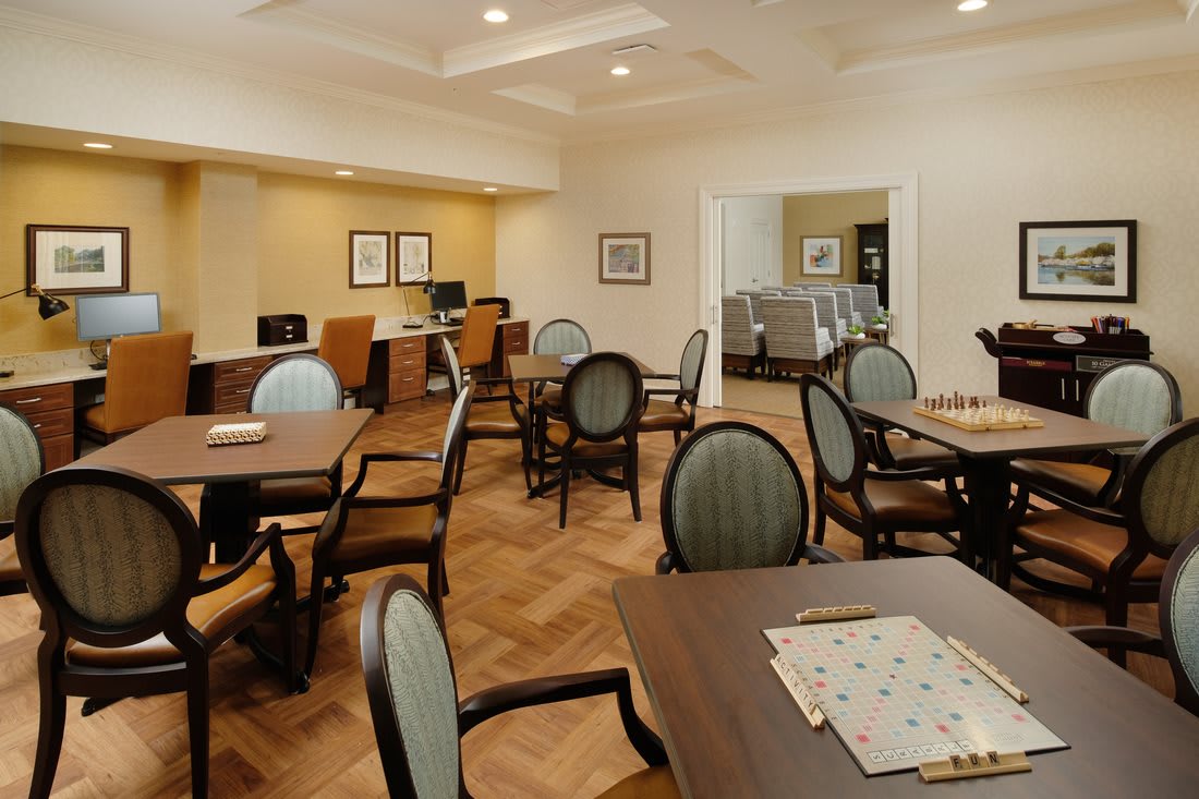 A well-lit community room with tables, chairs, and a computer station.