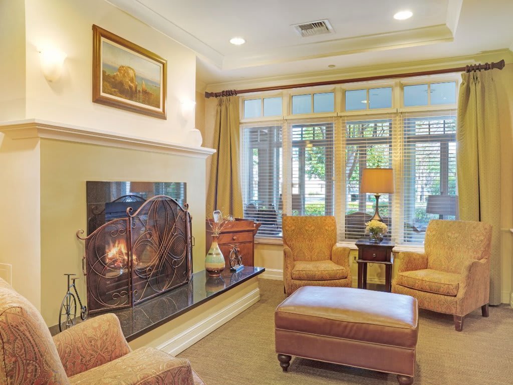 A cozy living room with a fireplace, armchairs, and large windows.